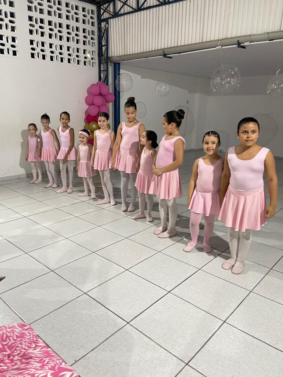 Turma de balé de collant rosa, enfileirada no salão