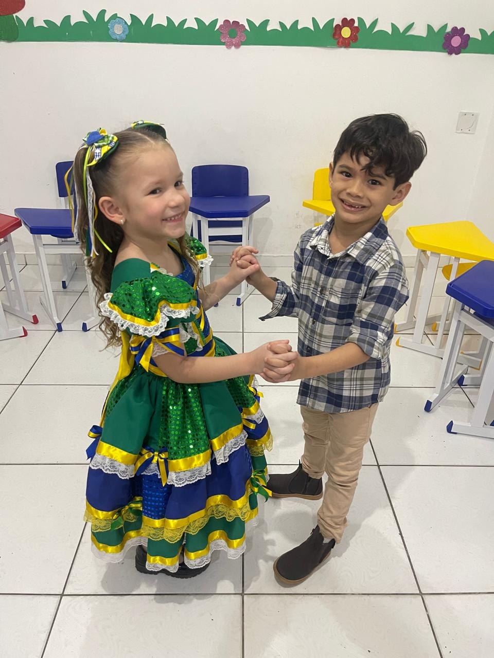 Menina de vestido de quadrilha e menino de camisa xadrez dançando